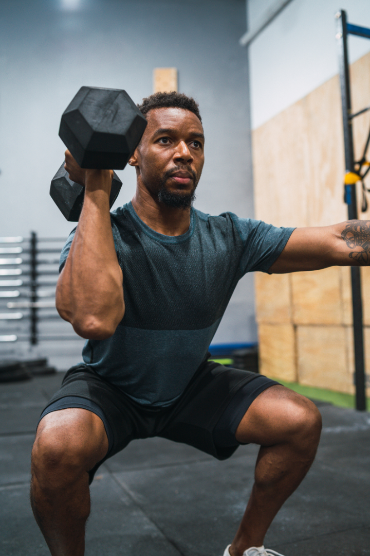 Man doing dumbbell squats in the gym while following a macro tracking plan for bulking from the Unchecked Fitness app